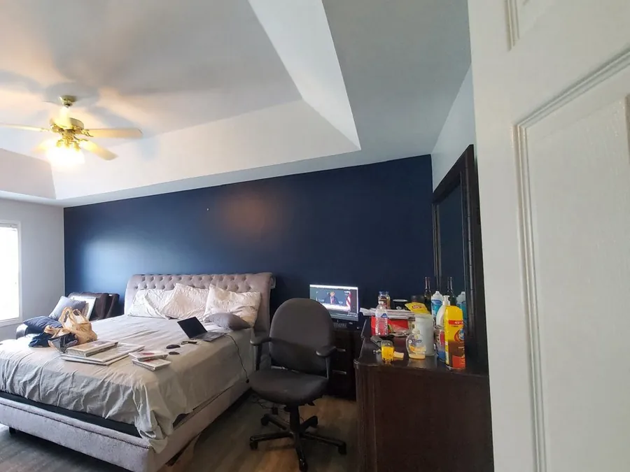 Bedroom after painting, with a navy accent wall and white tray ceiling
