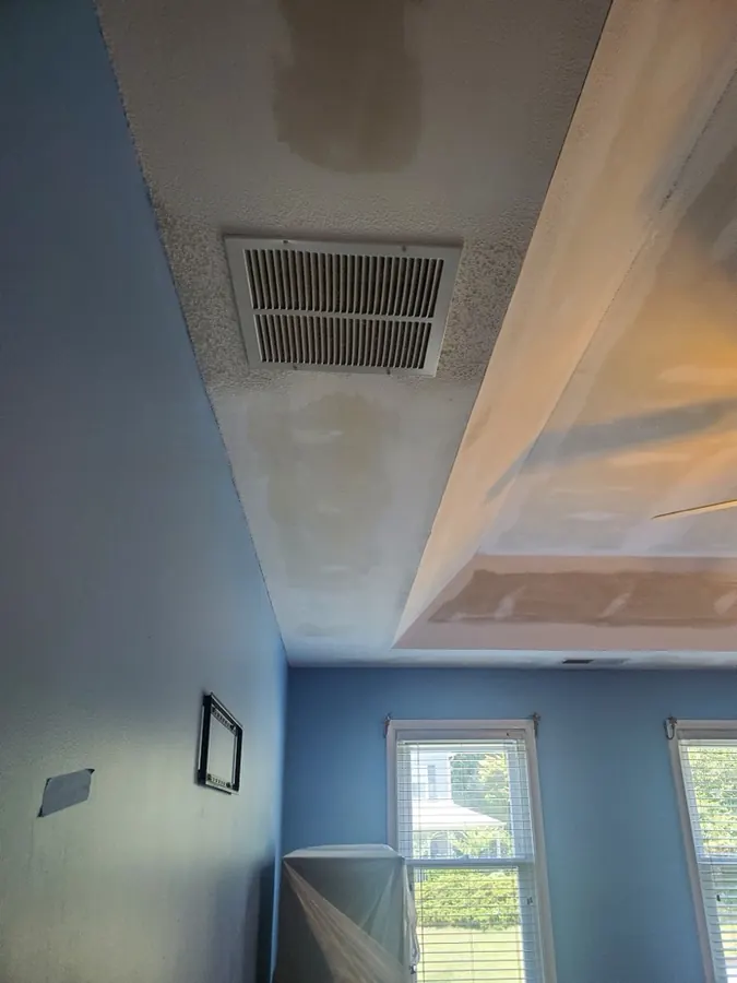 Bedroom ceiling with a water stain and blue walls before painting